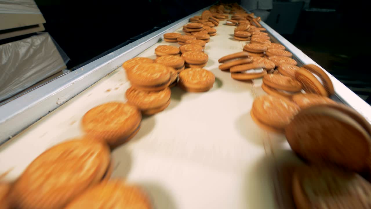 Biscuits are moving on the conveyor close view .