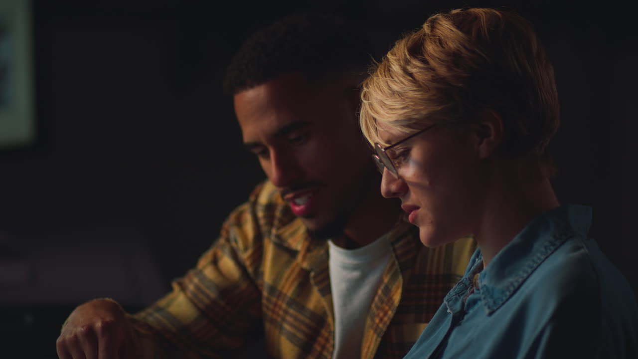 cerca de dos colegas de negocios en escritorios en la oficina trabajando hasta tarde en un proyecto de computadora juntos