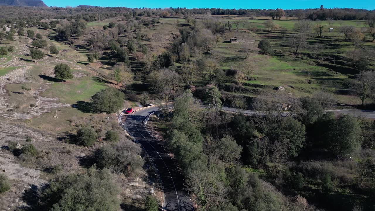 un coche en un camino sinuoso a través de un campo verde exuberante en la región de tavertet, vista aérea