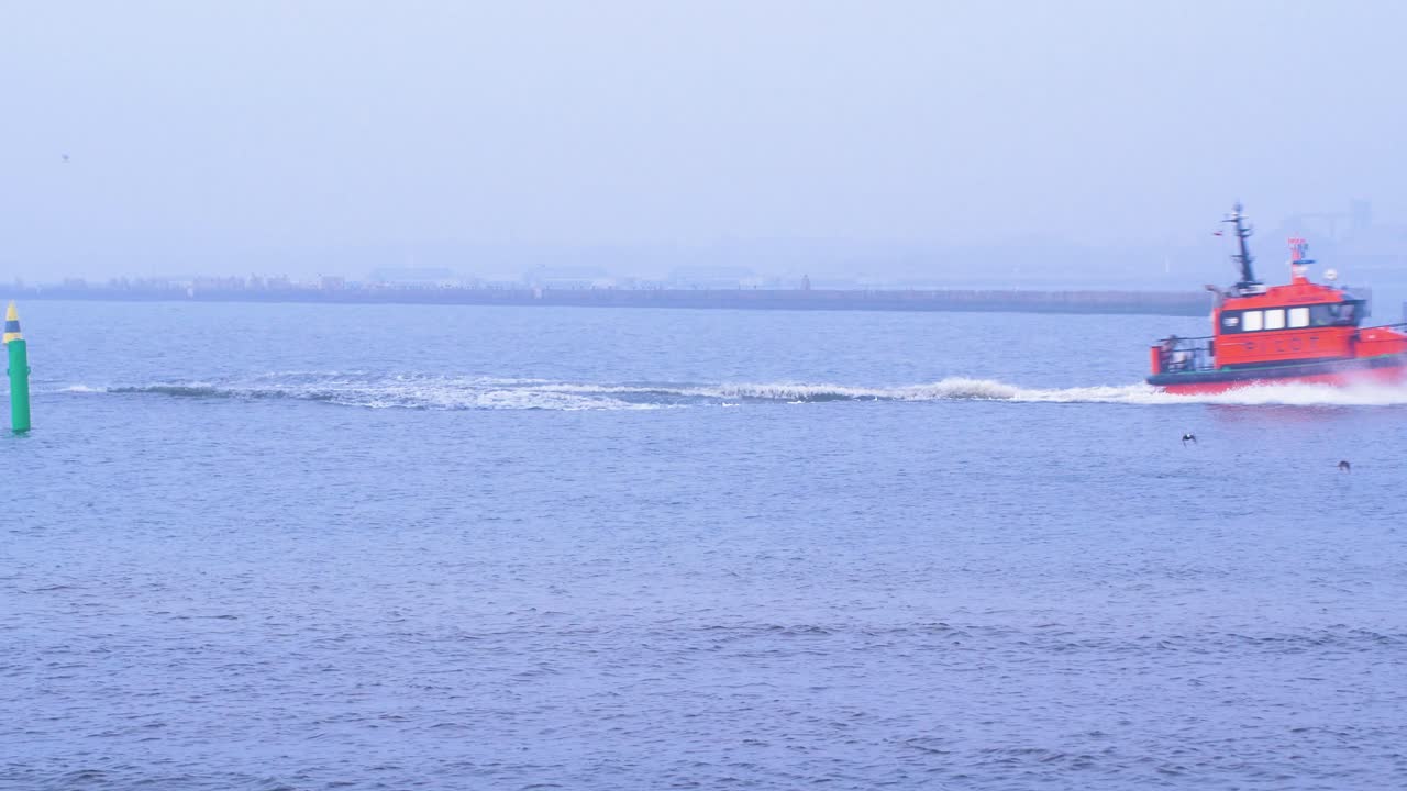 안개 낀 날 리파자 항구로 돌아가는 빨간 조종사, 전경의 돌 부두, 파도가 튀는 것, 먼 핸드헬드 미디엄 샷