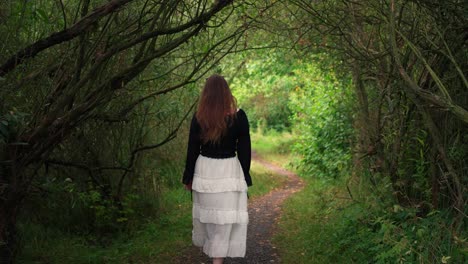 Young-girl-with-long-hair-in-a-skirt-walks-through-a-romantic-forest-in-slow-motion