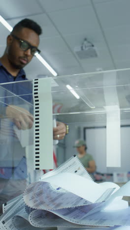 African-American-man-votes-for-presidential-candidate-in-voting-booth-at-polling-station,-then-puts-paper-ballot-in-box.-Male-US-citizen-during-National-Elections-Day-in-the-United-States.-Civic-duty.