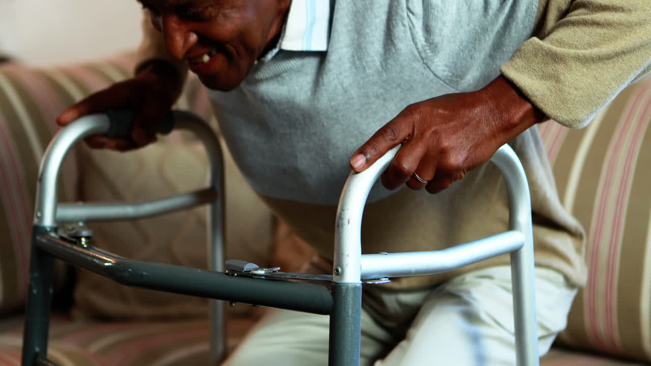 Senior man getting up from sofa with walker