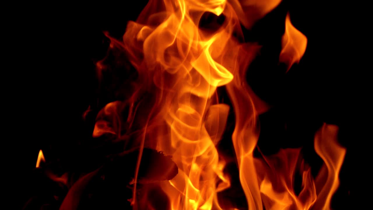 Process of burning wood with a bright flame on black background. Beautiful yellow, orange blaze fire texture at night. Close-up