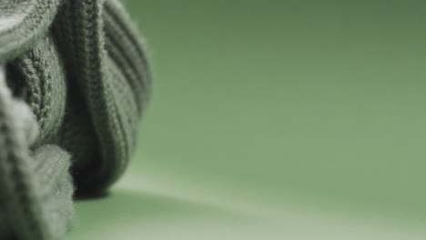 Micro-video-of-close-up-of-green-wooly-crochet-fabric-with-copy-space-on-green-background