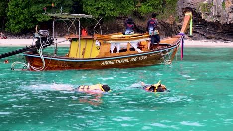 tourists snorkeling near a boat in krabi, thailand