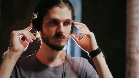 retrato del hombre sensual escuchando música con auriculares alrededor de la pared de ladrillo de un h abandonado