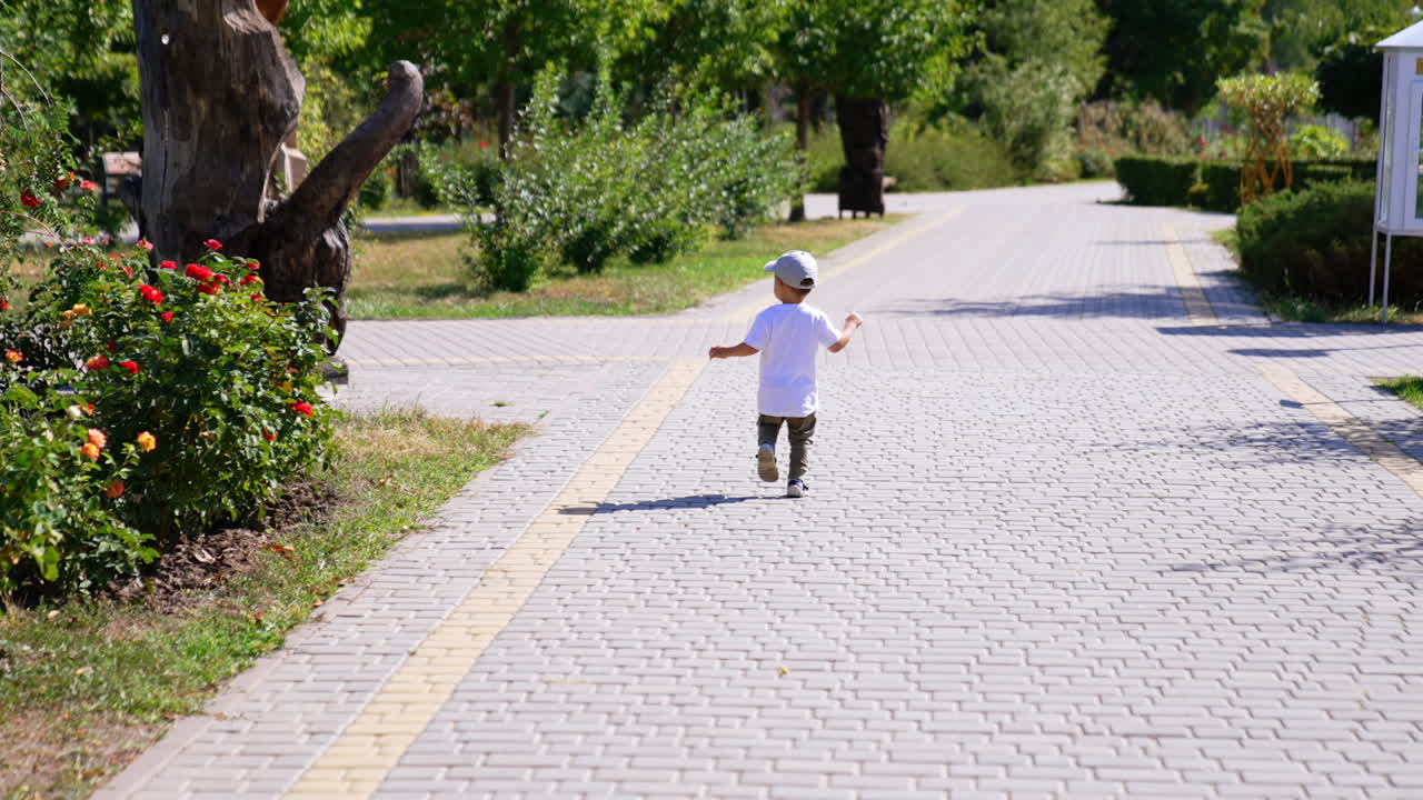 Catching up with a little baby boy running by the alley in the park. Toddler kid comes up to a wooden sculpture.