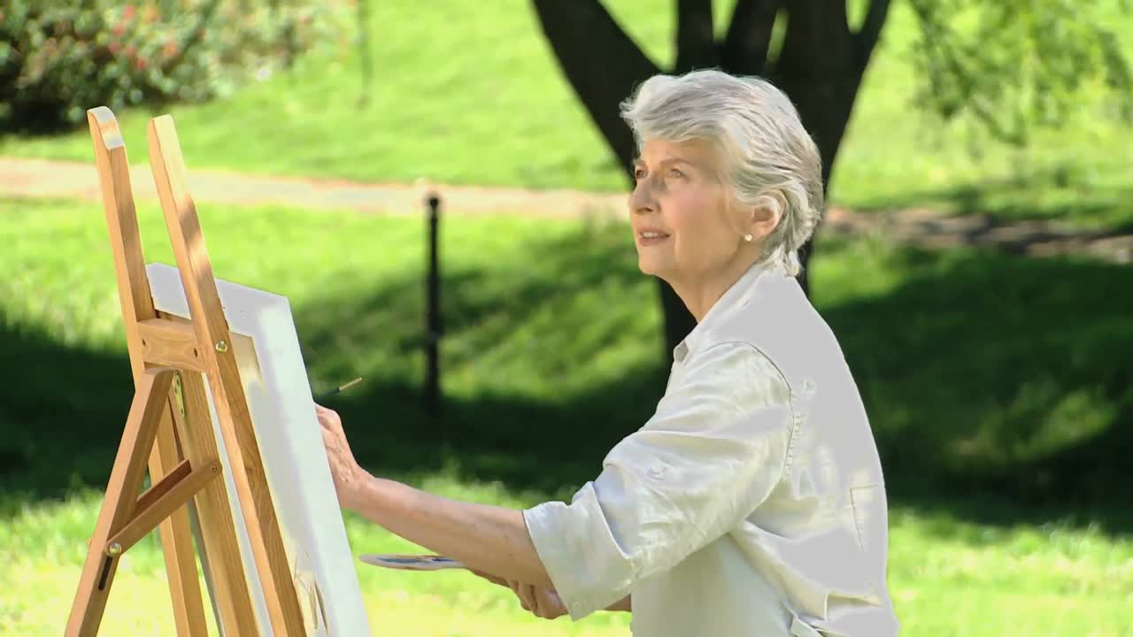 은 여자 가 캔버스 에 그림 을 그리고 있다