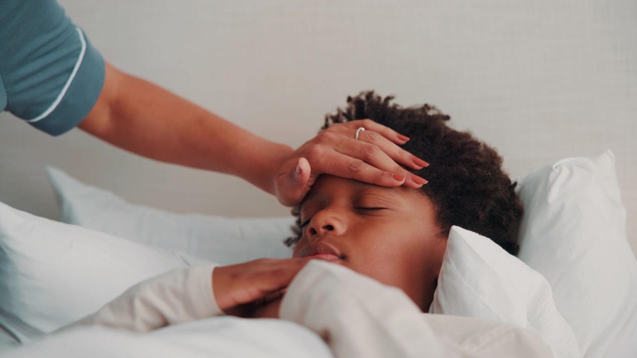 Mother Checking Temperature of Sick Child Sleeping in Bed