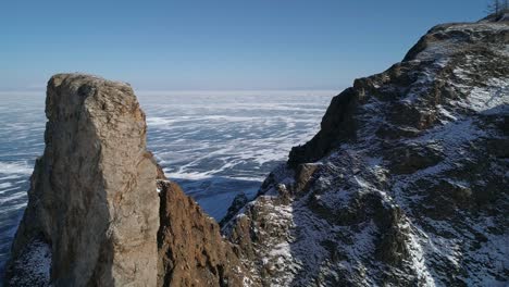 aerial orbital shot of cape khoboy, olkhon island. tall rocks in frozen lake baikal. popular touristic destination. winter landscape. panoramic view