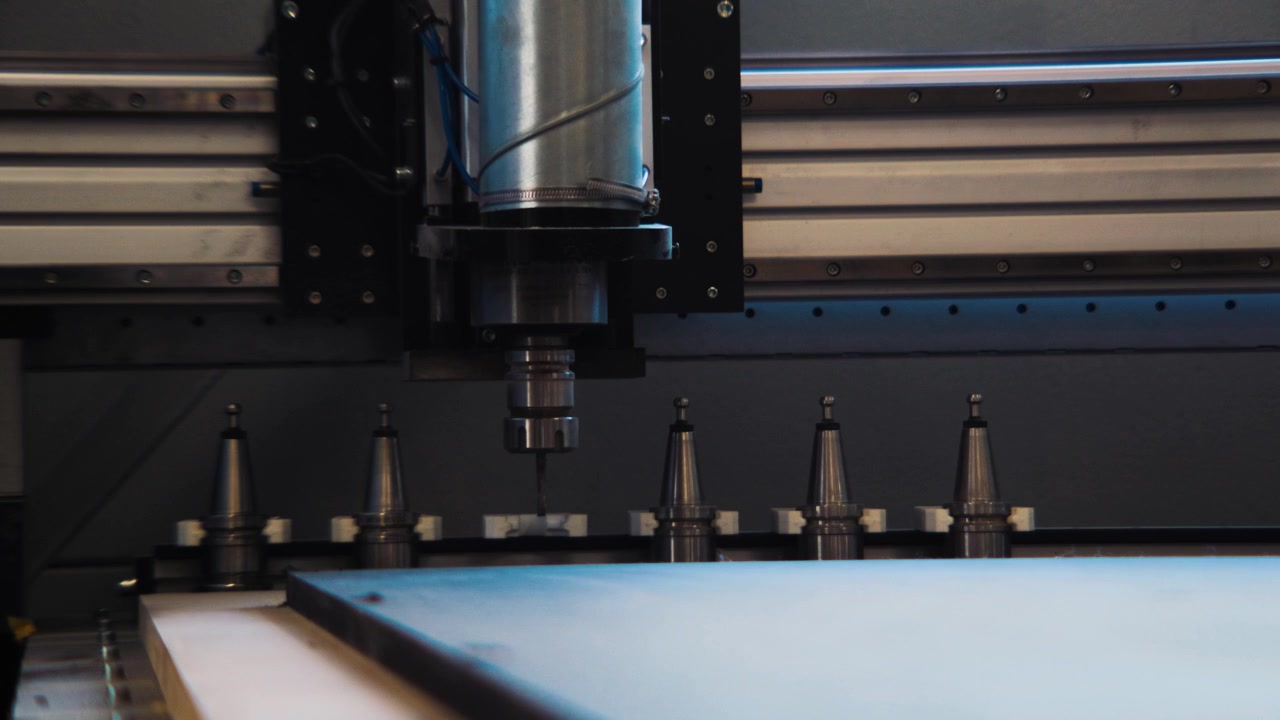 Vista frontal de um fuso CNC acima de uma fileira de porta-ferramentas dentro de uma máquina moderna de marcenaria