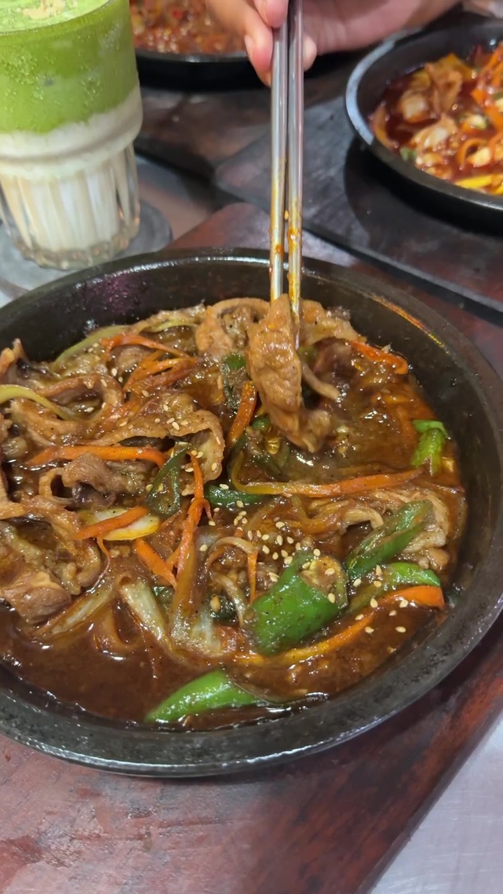 Seseorang Menggunakan Sumpit untuk Makan Daging Sapi Bulgogi Korea di Restoran