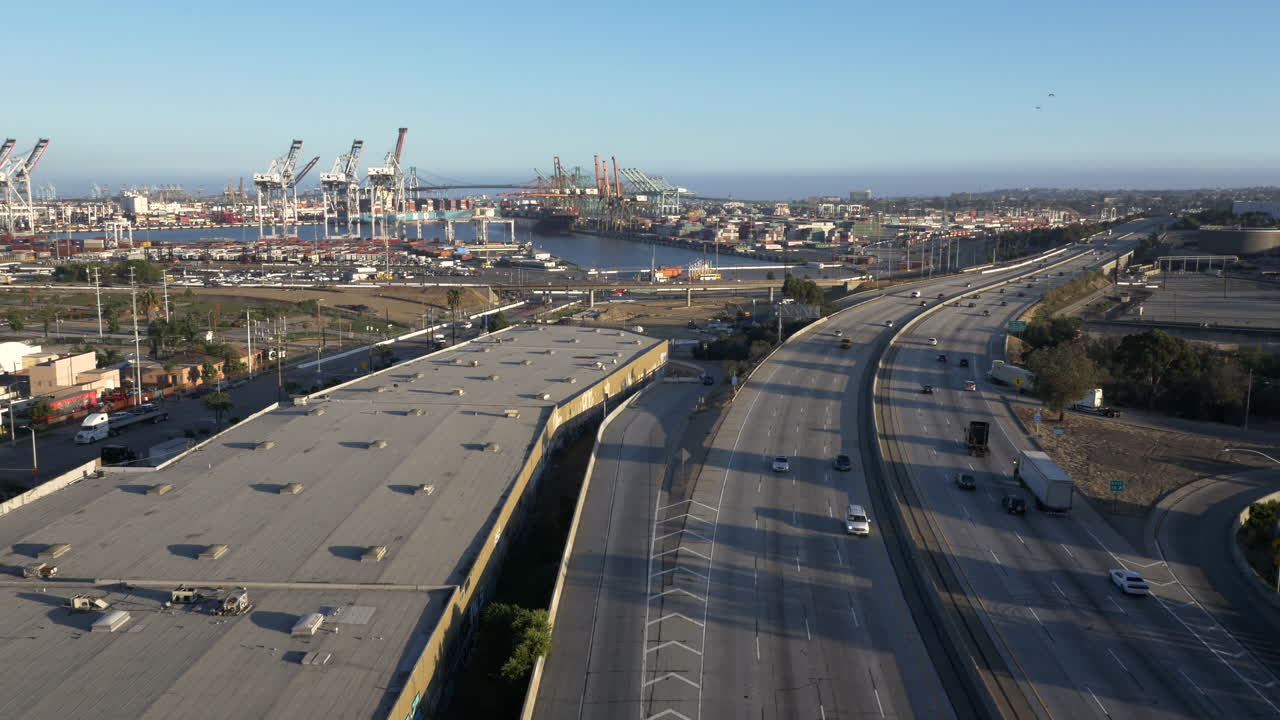 Aerial view of a highway leading to a bustling shipping port with cranes and containers