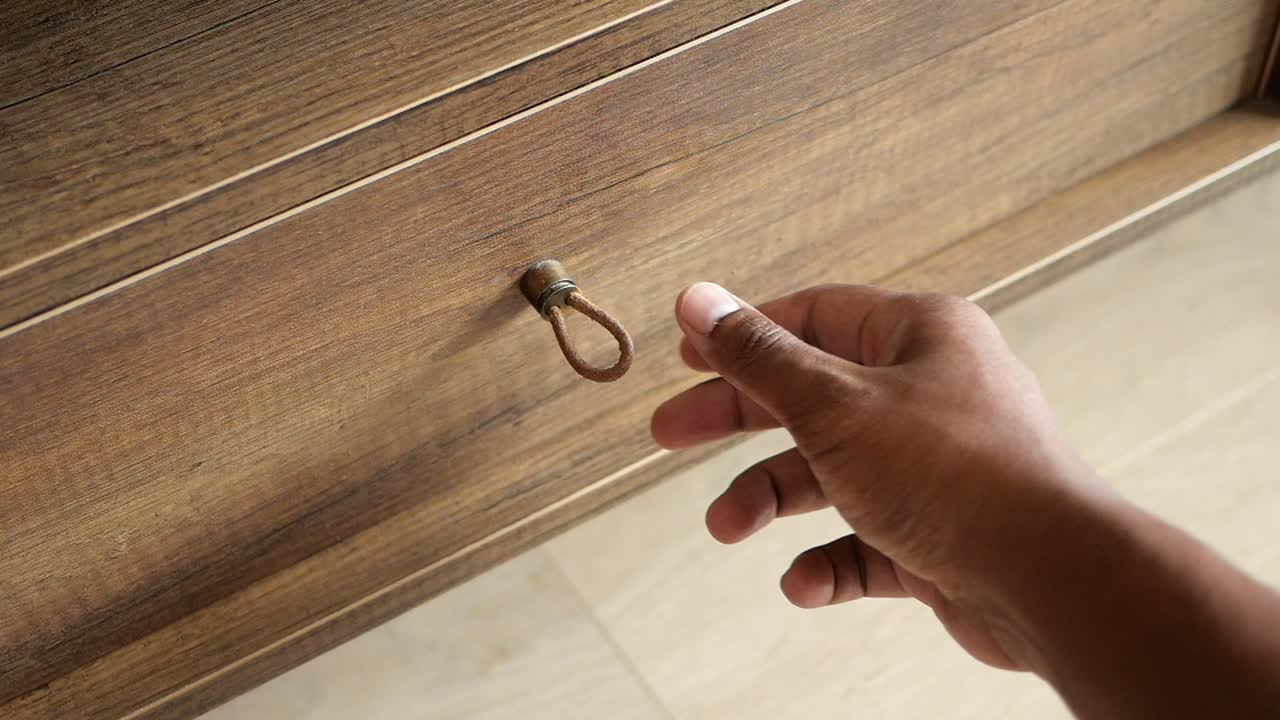 Person opening a brown wooden drawer