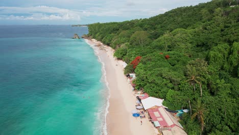 aerial shot of pristine white beach with jungles in uluwatu, bali, indonesia