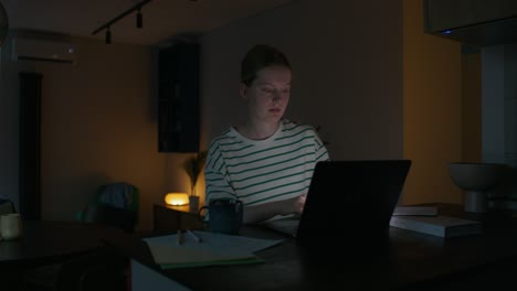 teenage girl working on laptop in kitchen at night