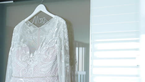 wedding dress hanging from hanger with mrs. logo