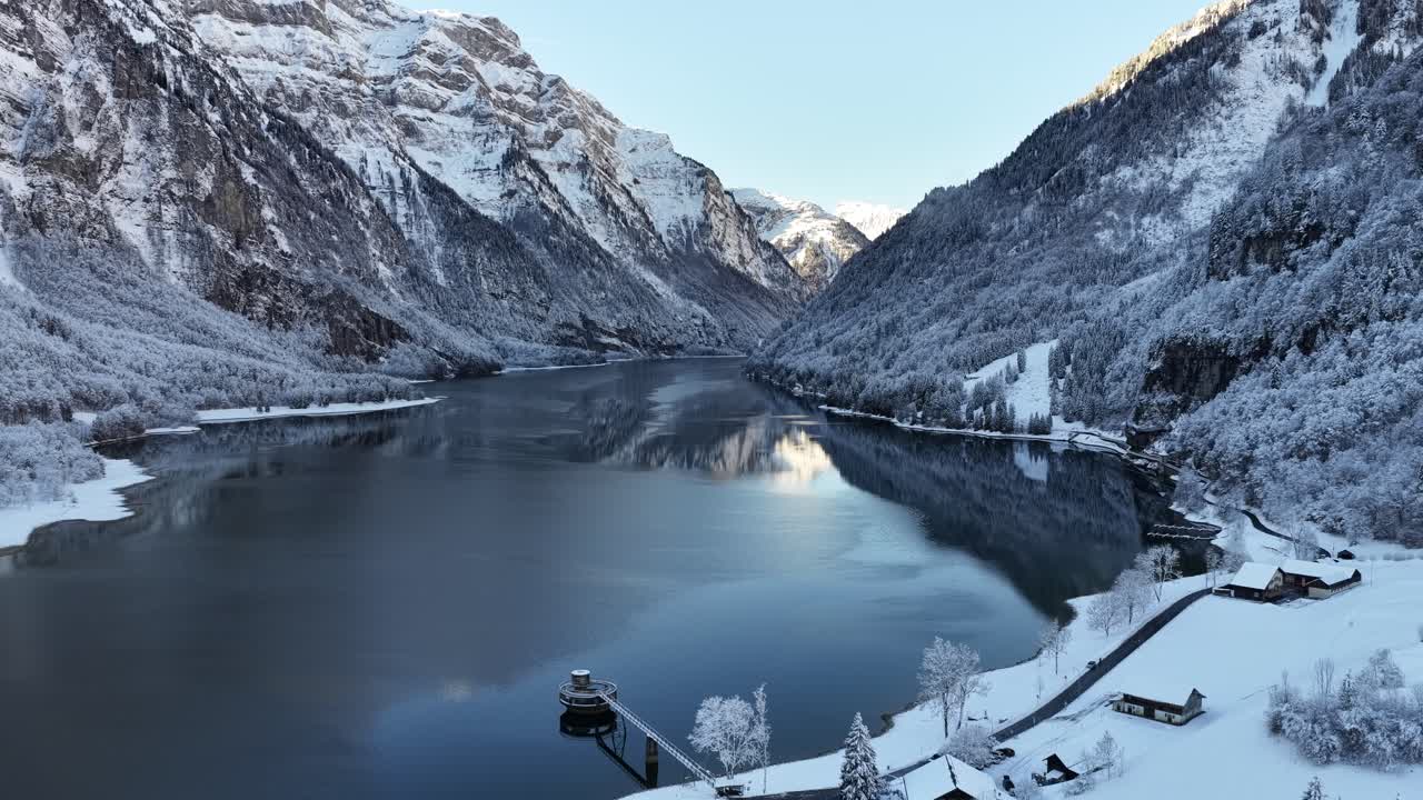 Pristine winter scene of snow-covered mountains and icy Klontal Lake in Switzerland, captured from above