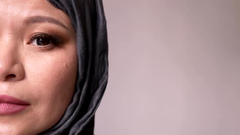 closeup half-face shoot of adult attractive muslim female in hijab looking forward and turning to camera with isolated background