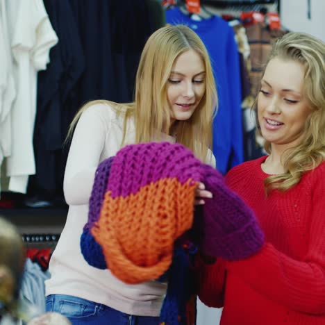 two friends choose warm winter clothes in the store