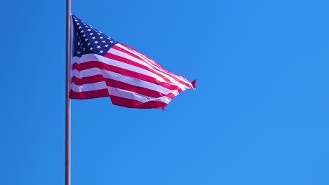 american flag waving on clear blue sky background, vibrant red white and blue colors against copy space