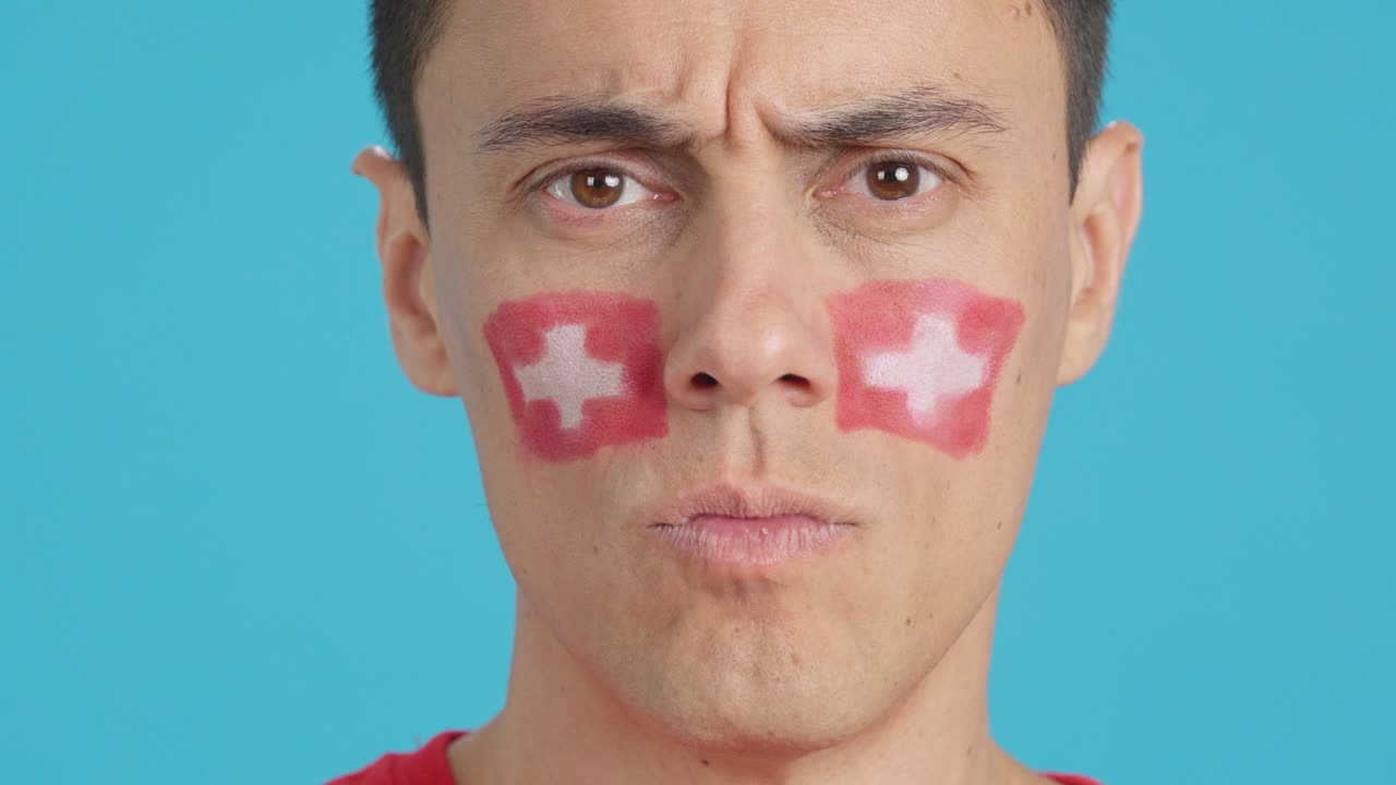 Serious man with a swiss flag painted on the face