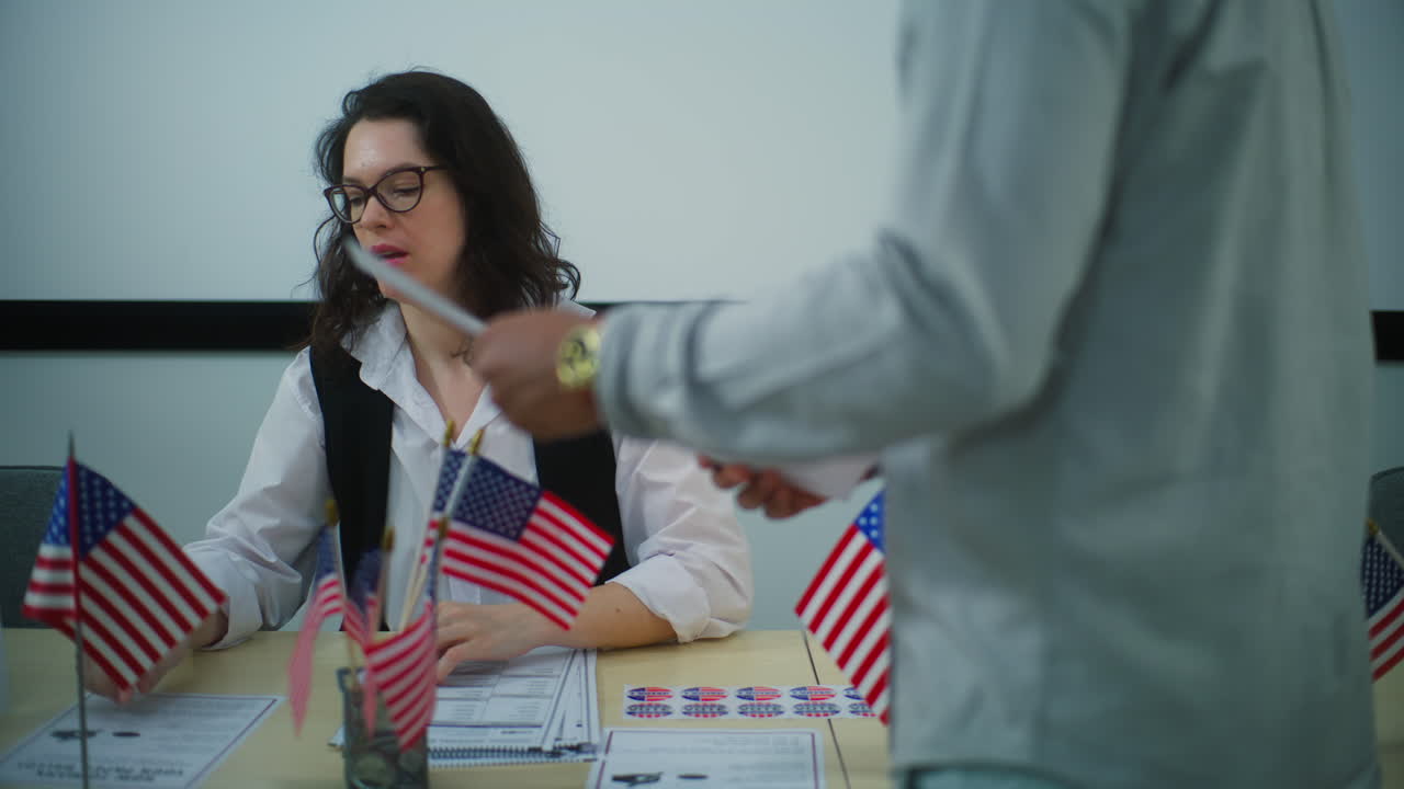 African American Male Voter Talks with Female Polling Officer African American Man Takes Paper Ballot for Voting at Polling Station Male Voter Talks with Female Polling Officer National Election Day in the United States of America Civic Duty and Democracy