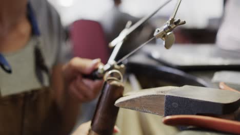 trabajadora biracial moldeando joyas con sierra en un taller en cámara lenta
