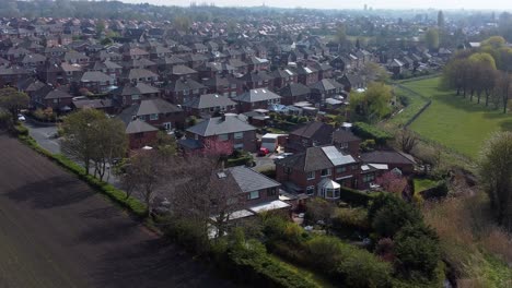 Countryside-housing-estate-aerial-view-flying-above-England-farmland-residential-neighbourhood-homes-orbit-left