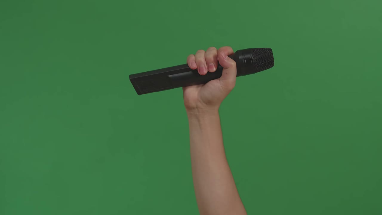 Male Hand Holding Microphone Against Background Green Screen Chroma Key. Close Up Mic, Live Press Conference, Karaoke, Singer Performance