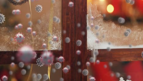 Animation-Von-Covid-19-Zellen,-Die-Sich-über-Weihnachtsdekorationen-Bewegen,-Gesehen-Durch-Ein-Fenster-Im-Hintergrund