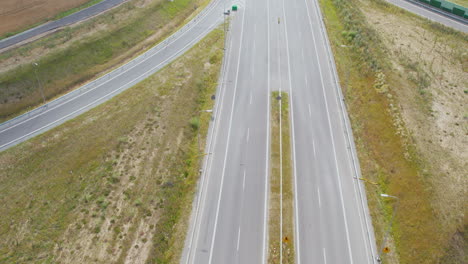 Toma-Aérea-Inclinada-Hacia-Arriba-De-Una-Carretera-Vacía-En-El-área-Agrícola-De-Polonia-Durante-El-Día