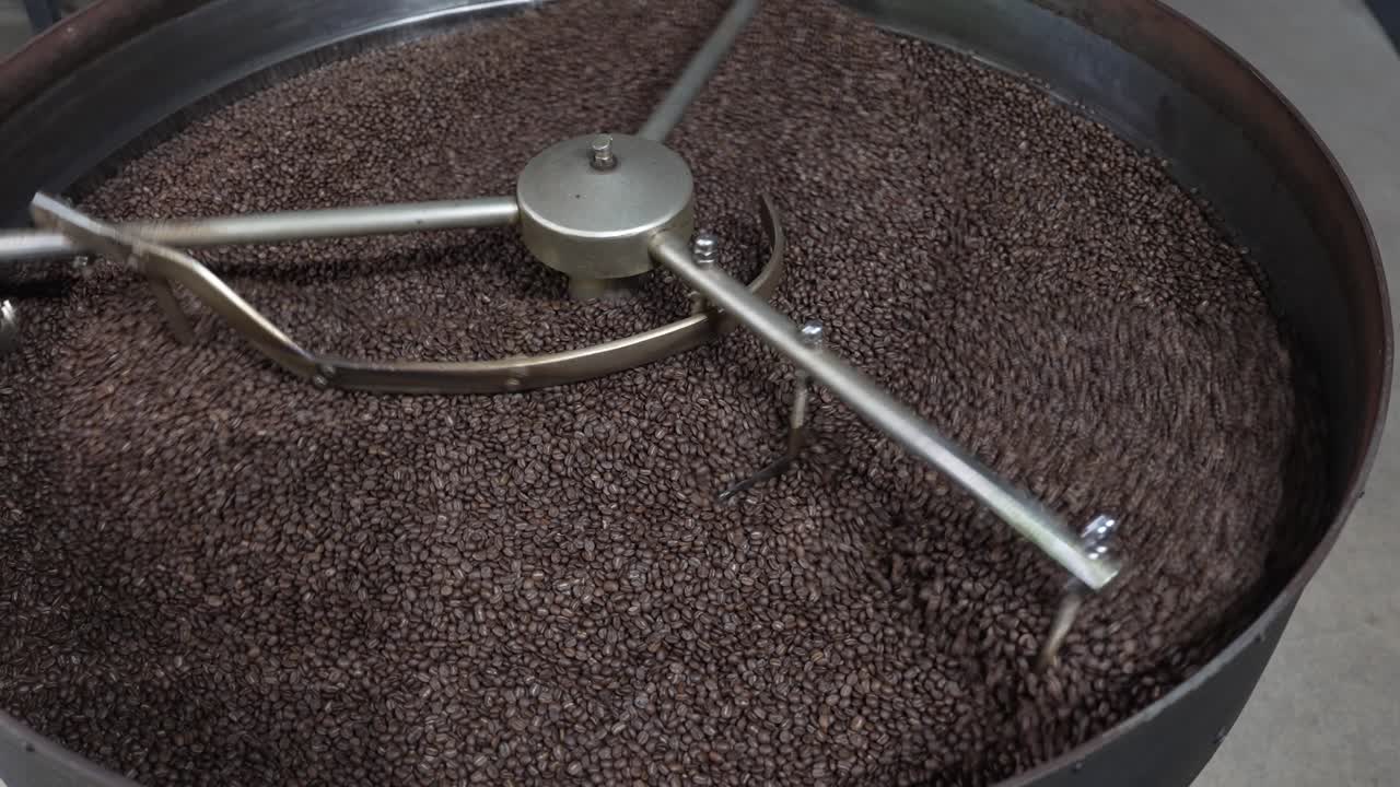 Roasted beans shifting inside an industrial cooling tray