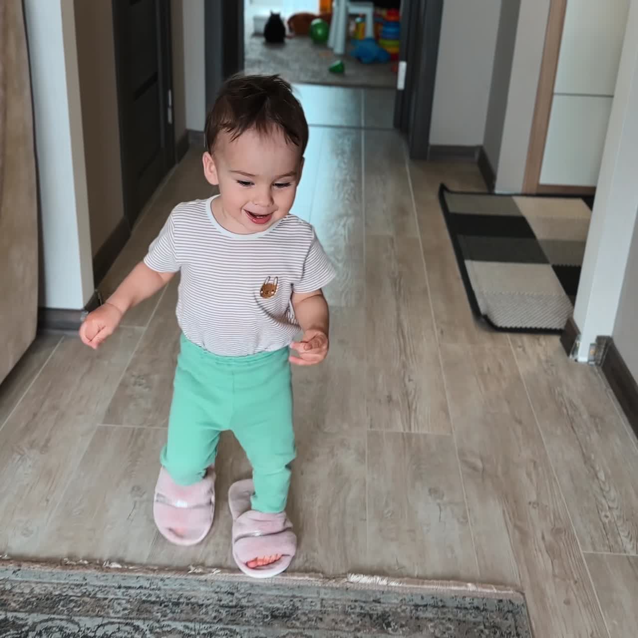 Happy baby boy put on mom's slippers and walks in them by the room. Adorable child plays at home. Top view