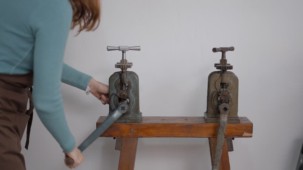 Woman using antique metal rolling/pressing machines