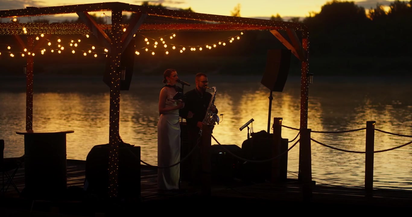 Muziekduo op een pier bij zonsondergang
