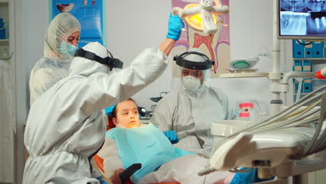 dentist technician in coverall drilling kid tooth in dental clinic