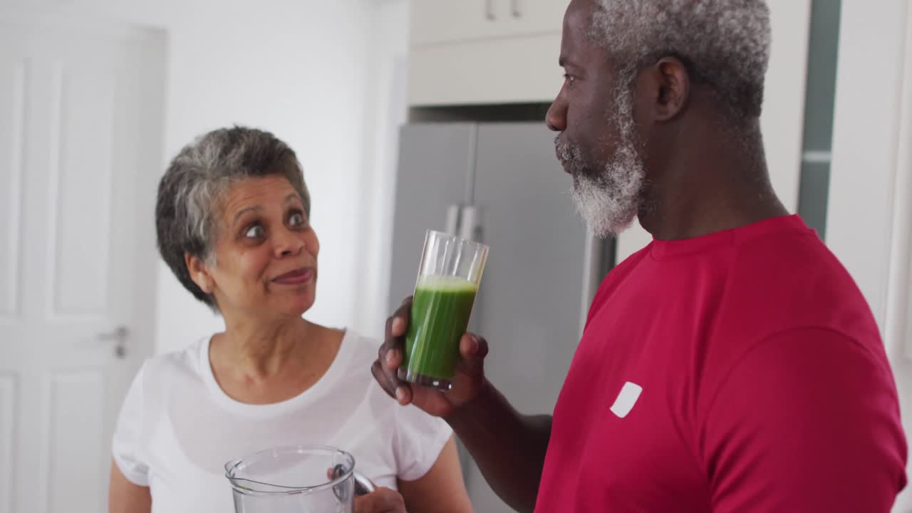 Senior african american man and woman drinking fruit and vegetable health drinks at home
