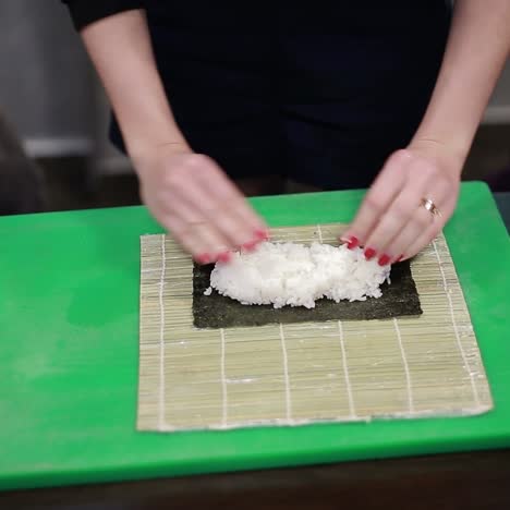 mujer chef llenando rollos de sushi japoneses