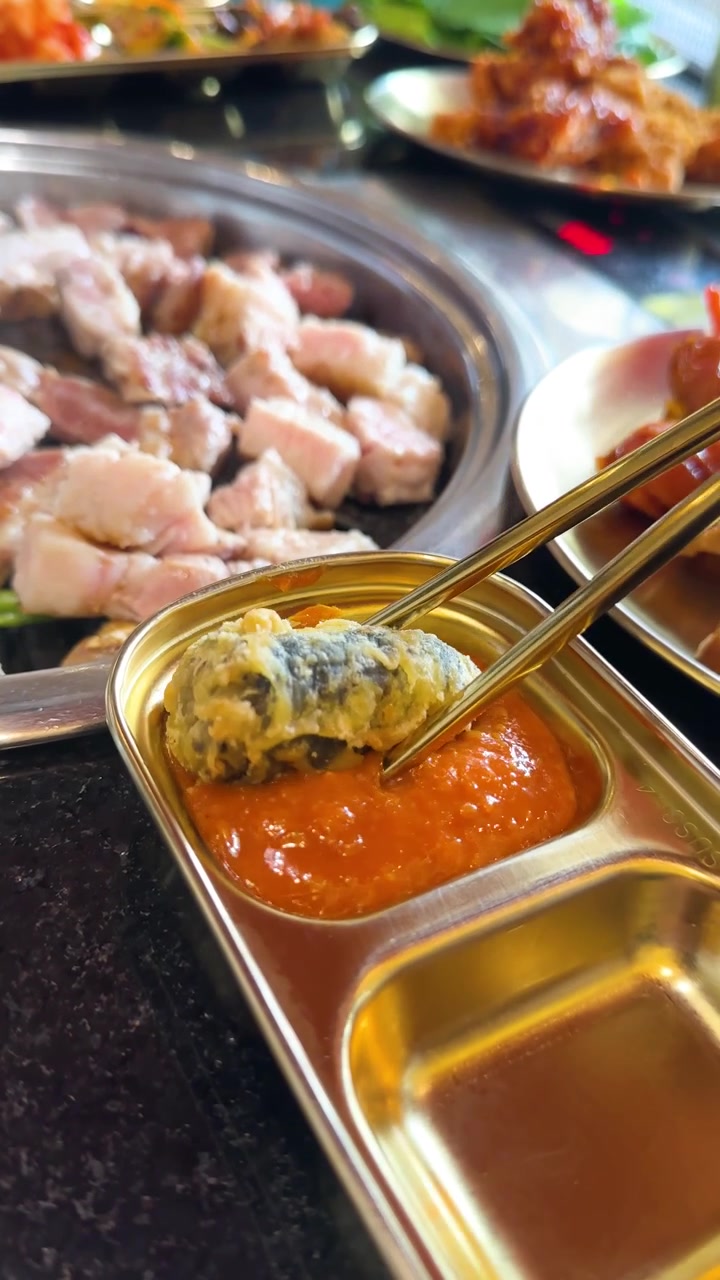 Hashis mergulham rolo de alga frita em molho picante em uma mesa vibrante de restaurante de churrasco coreano