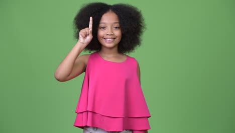 young cute african girl with afro hair pointing finger up