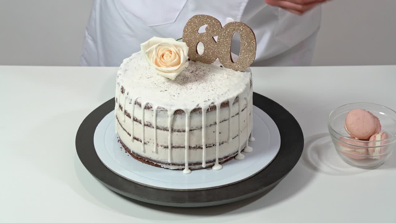 hermoso pastel de cumpleaños, decorado con macarrones y una rosa, siendo presentado con orgullo por una panadera.
