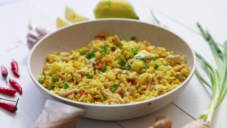 delicious fried rice with chicken and vegetables served in pan  placed on white wooden table