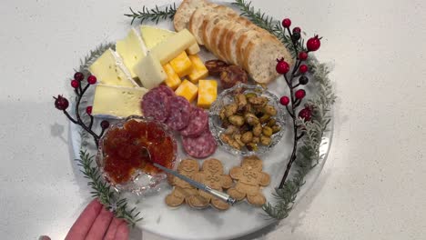 holiday cheese plate with assorted cheese, nuts, crackers, salami, and bread