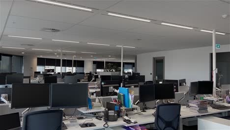 high quality dolly shot over empty desks in a large and deserted office building with unattended workstations, during the covid-19 pandemic lockdown, with all employees working from home