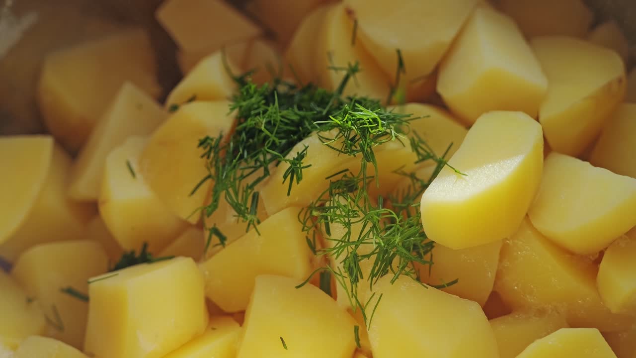 Primo piano al rallentatore di patate fumanti guarnite con aneto fresco fragrante.