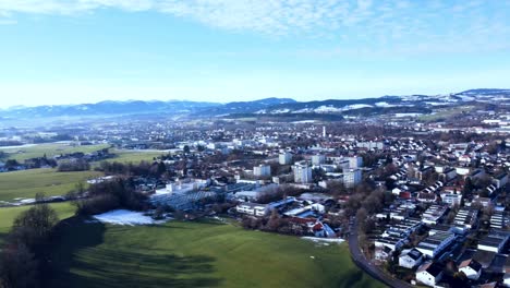 Friedliche-Stadt-In-Süddeutschland-Mit-Chaotisch-Angelegten-Häusern-Im-Vordergrund,-Schneebedeckte-Hügel,-Die-Sich-Zeigen,-Nachdem-Die-Drohne-Zur-Seite-Schwenkt