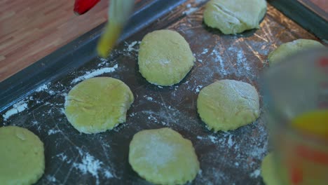 Bürsten-Der-Spitzen-Der-Geformten-Scones-Auf-Einem-Backblech-Weibliche-Hand