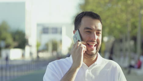 smiling young man walking on street and talking on phone.